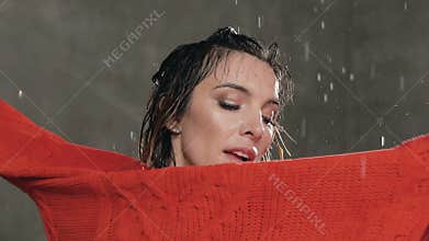 dancer girl in red sweater dancing emotional modern dance under the water rain in the studio, she splashes drops of