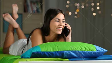 Girl calling on phone on a bed at home