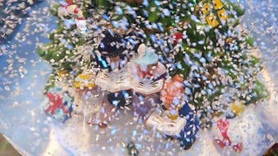 Christmas glass ball in snow with miniature characters sing Christmas carols