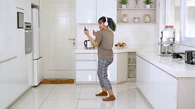 Woman dancing while listening music in kitchen