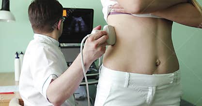 Male doctor examining the woman`s right kidney using an ultrasound scanner.