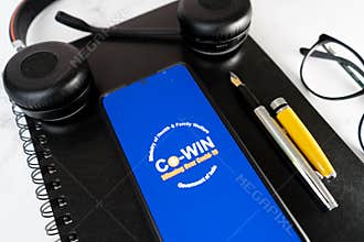 Mobile phone app showing the COWIN app a pen and notebook for vaccine booster registeration during the COVID pandemic