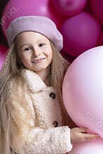 Girl in beret playing with pink, purple balloons, hildrens emotions. beautiful child on holiday. Kid birthday party concept