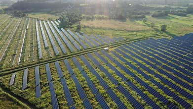Top view of a massive photovoltaic power station located in a field at sunset. Solar energy power plant. Ecological clean energy