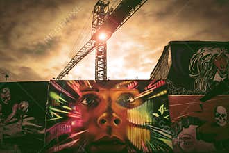 Graffiti wall with construction crane in background.