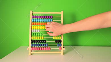 Female hand slowly counts on a children&#x27;s wooden abacus. Close-up of flipping wooden circles. Counting on a