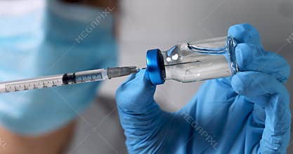 Nurse filling syringe with vaccine for vaccination from blank glass vial