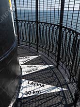 Signs on the floor on top of the building of  Sõrve lighthouse showing the distance to Latvia.