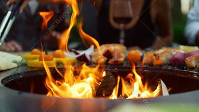Closeup fire flames burning in bbq grill on backyard. Vegetables cooking outdoor