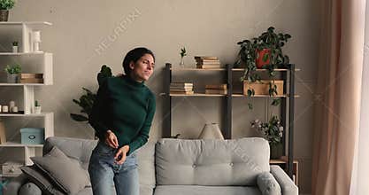 Overjoyed young crazy woman dancing alone in living room.