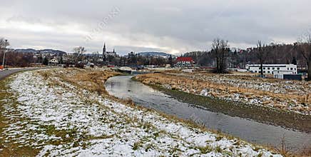 Ultra wide shot of white snow fall spread over grass by the river in country side of South Poland during winter with over cast