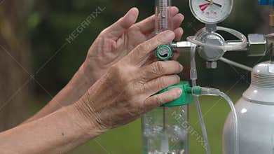 Elderly woman holding flow regulator with oxygen cylinder