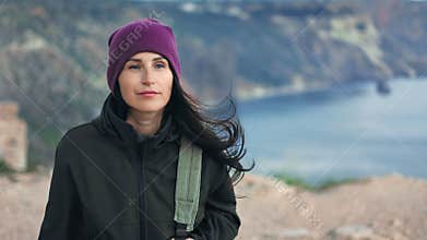 Active hiker female walking on mountain top admiring nature sea at windy weather extreme travel