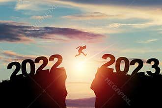 Welcome merry Christmas and happy new year in 2023,Silhouette Man jumping from 2022 cliff to 2023 cliff with cloud sky and