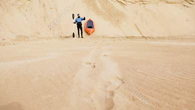 Man stand with paddle an raft boat at sand dune