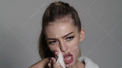 Trans gender concept. Woman shaving face. Angry young woman with foam on the face and a razor blade.