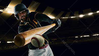 Poster with professional baseball player with baseball bat in action during match in crowed sport stadium at evening