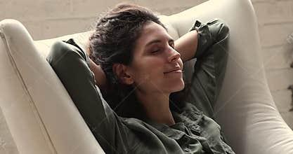 Peaceful young woman resting in comfortable armchair.