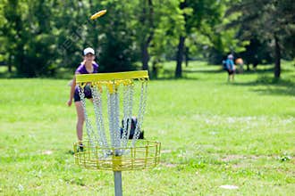Young woman playing flying disc golf sport game in the park