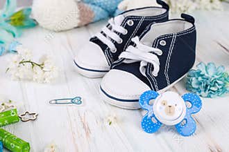 Baby first sneakers and dummy on floral wood background. Little baby shoes. Child planning. Pregnancy concept. Baby boy first