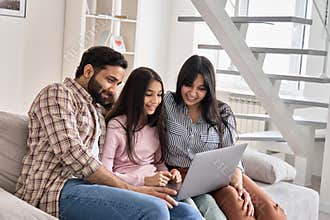 Happy indian family couple with teen daughter using laptop computer at home.