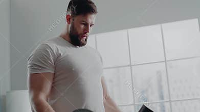 Fitness trainer practices biceps curl with large dumbbells