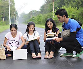 Students sitting on the road and sharing notes.