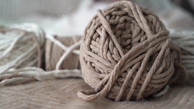 Boho-style wool threads lie on the bed, a woman's hand takes a ball. Suitable for macrame, banners and craft