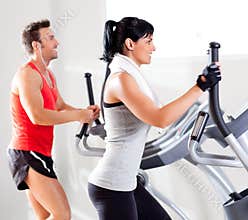 Man and woman with elliptical cross trainer at gym