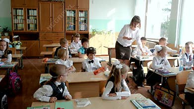 In elementary school class: teacher walks between rows of diverse children, explains lesson: Gomel, Belarus - 09.01.2020