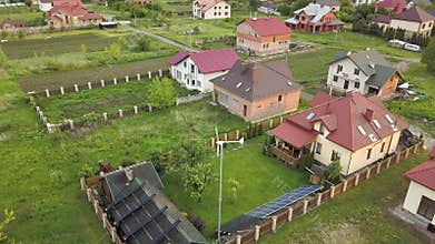 Aerial view of suburban homes and private house with green grass covered yard, solar panels on roof, swimming pool with blue water