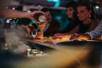 Bartender serving cocktails to a group of friends at a lively bar