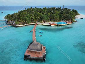 A jetty with a bridge leading to a small island with coconut trees