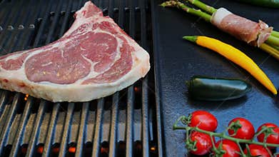 Beef steak with bone on cast iron grill barbecue, vegetables asparagus with bacon. Top view