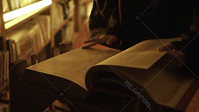 Man reading large mysterious book. Stock footage. Close-up of mysterious man reading ancient forbidden book in library