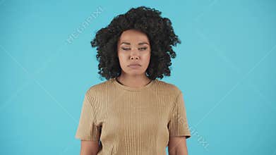 A young woman looks into the camera and breathes heavily, holding back her anger. A black woman with curly hair stands