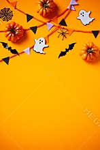 Happy Halloween flat lay composition with pumpkins, bats, ghosts, spiders, bunting flag garland on orange background. Halloween