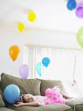Girl Looking Up At Balloons On Sofa
