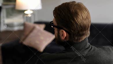 Man sitting on sofa with lamp in background in cozy living room against home interior