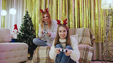 A group of festive friends joyfully enjoying video games together inside a cozy living room filled with holiday