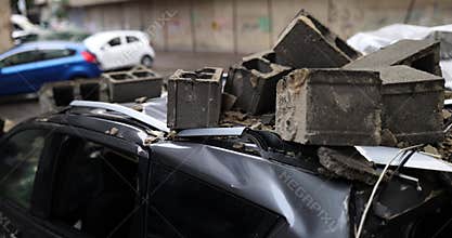 car is damaged by falling debris on city street
