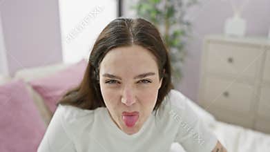 Attractive young woman in pyjamas feeling ill, sitting on bed holding aching belly. painful stomachache, a battle with nausea and