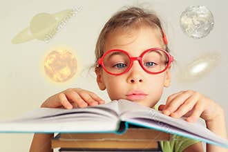 Girl in glasses studies astronomy from a book,