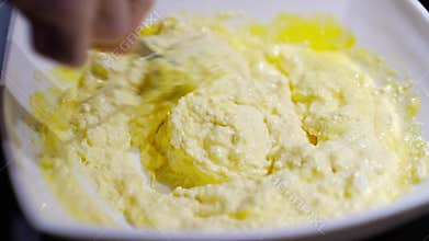 A woman&#x27;s hand mixes the dough with the added flour with a spoon.