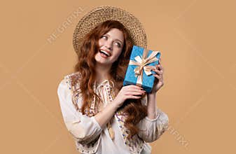 Happy woman gift box on beige background. Lady smiling,interested what& x27;s inside