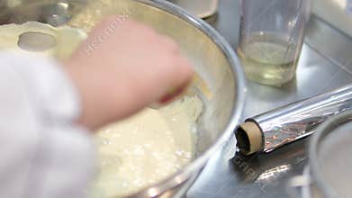 Add flour to. woman's hand mixes the dough with the added flour with a spoon. Making pastries at home.