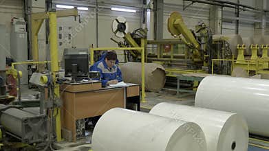 Storekeeper notes in form counting paper rolls at plant