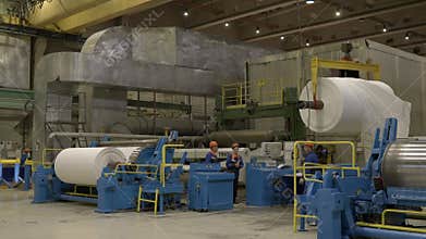 Workers control transportation of paper roll with crane