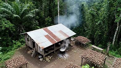 Aerial View of Rural Village Hut and Cassava Processing in Rainforest Environment with Smoke Rising from Cooking Fire