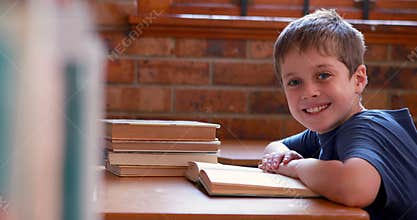 Little boy reading book in classroom